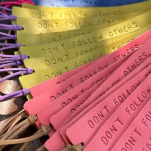 Marcadores de livros em couro multicoloridos com a frase “Don’t follow others, create your own world”.
