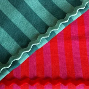 Guardanapos de tecido com padrão às riscas em tons de verde, azul, rosa e vermelho com acabamento ondulado