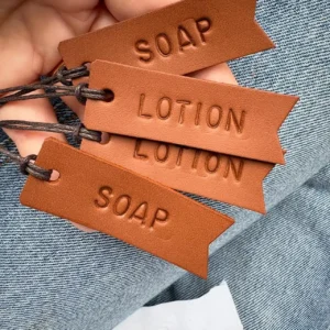 Etiquetas em couro personalizadas com as palavras SOAP e LOTION feitas à mão pela Jane-Made