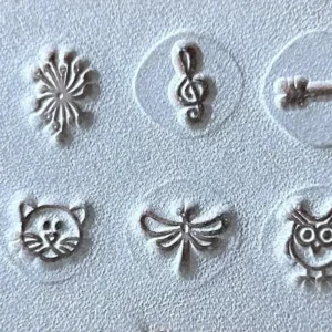 Símbolos em relevo no couro para personalização — cruz, coração, flor, clave de sol, âncora, infinito, estrela, gato, libélula, coruja e árvore.